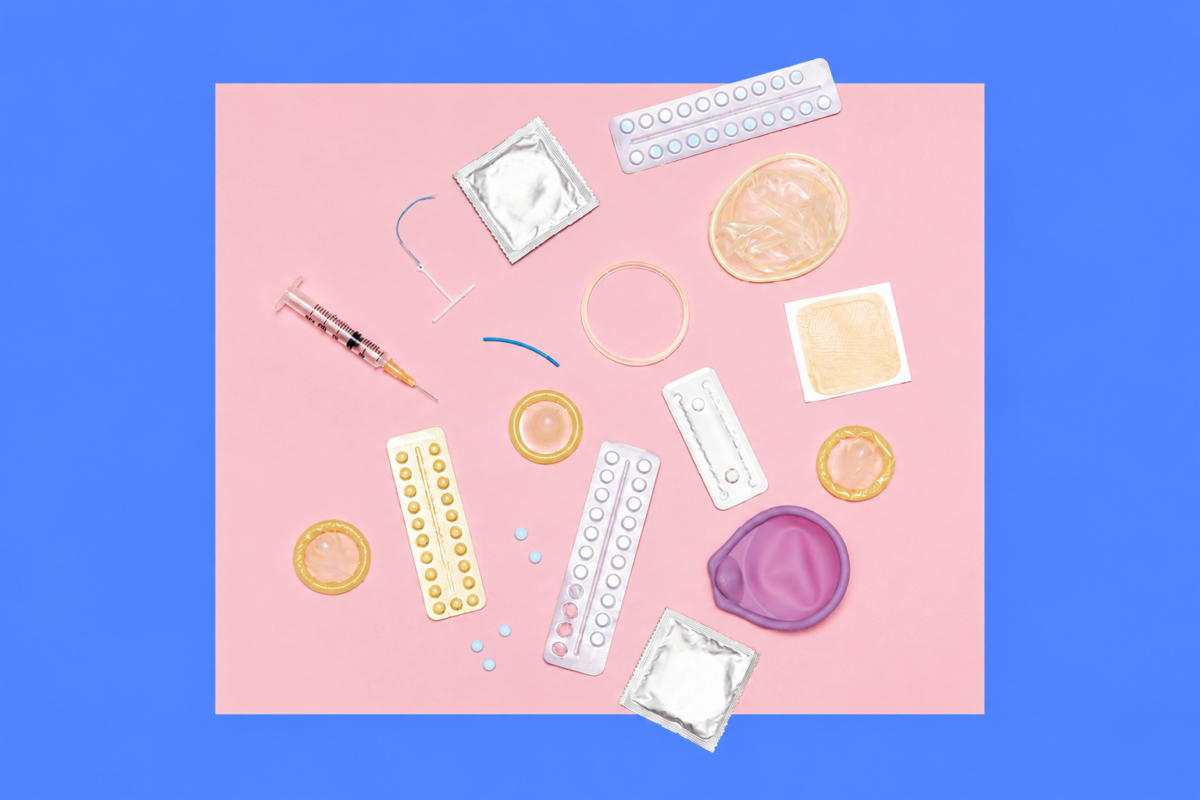 Assorted sexual health items scattered on a pink surface, including condoms, pill blister packs, a syringe, lubricant rings, and a purple sex toy with a blue backdrop.