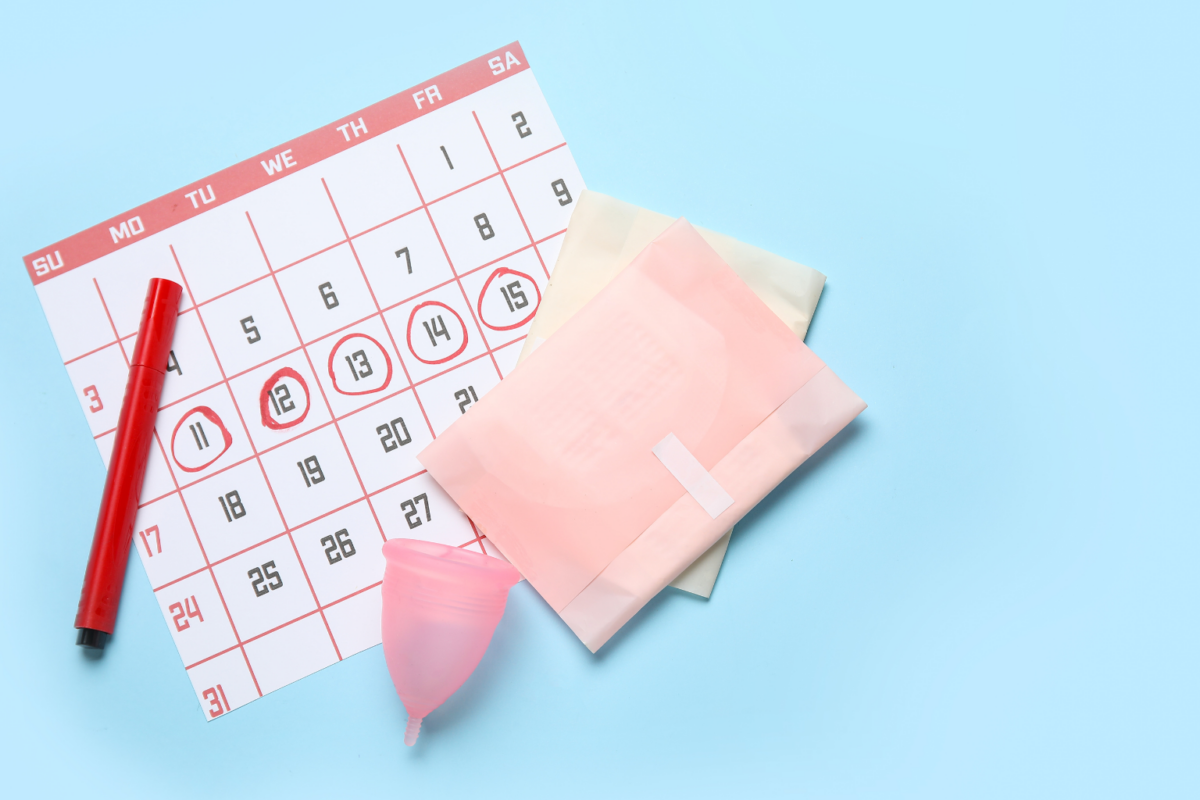 Calendar page with several dates circled in red, a red marker, and pink menstrual products on a light blue background (period planning scene).
